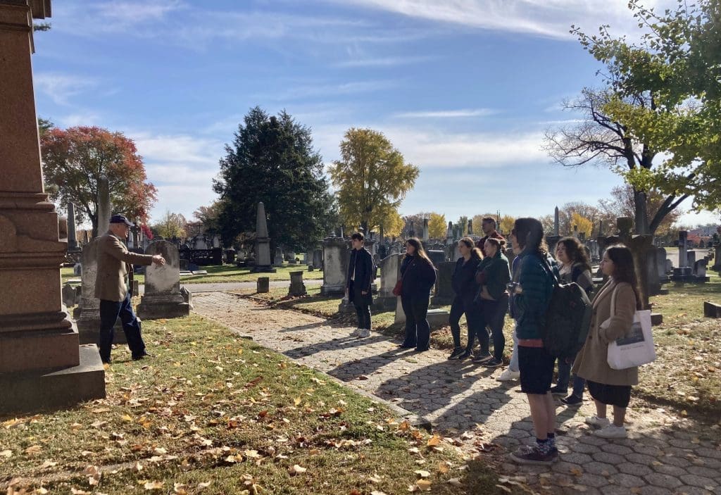 Students lined up on a path in Greenmount Cemetery in front of Enoch Pratt's tombstone